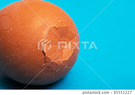 Brown cracked egg on a blue background 85551227
