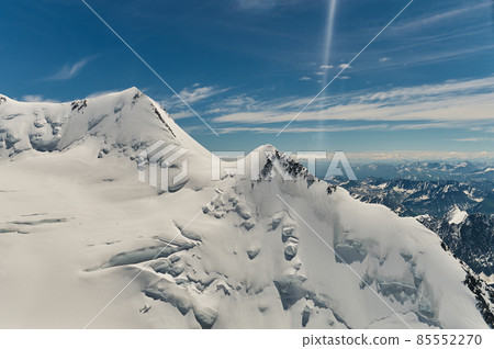 Minimalist view of snow-capped mountain wall in thick low clouds in sunshine. Scenic bright mountain landscape with white-snow peak among dense clouds in blue sky. Wonderful scenery with snowy top. Minimalist view of snow-capped mountain wall in thick low clouds in sunshine. Scenic bright mountain landscape with white-snow peak among dense clouds in blue sky. Wonderful scenery with snowy top. 85552270