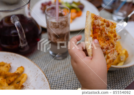 Asian child holding slice of delicious hot pizza over table. Asian child holding slice of delicious hot pizza over table. 85554092