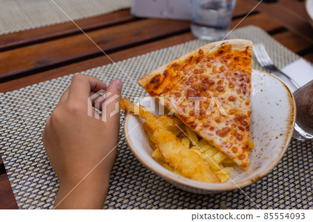 Asian child holding slice of delicious hot pizza over table. 85554093