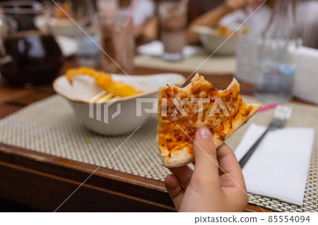 Asian child holding slice of delicious hot pizza over table. Asian child holding slice of delicious hot pizza over table. 85554094