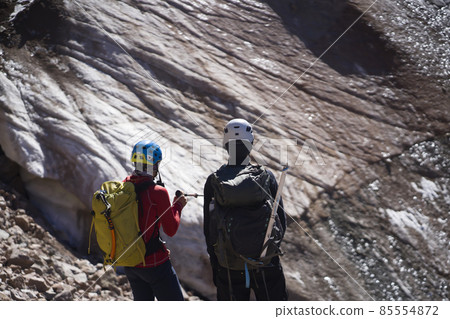 Two men climbs to the top of the mountain. 85554872