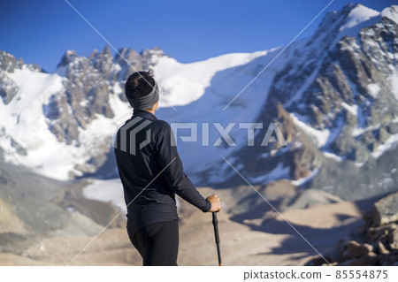 Traveler with trekking poles is walking in the snowy mountains. 85554875