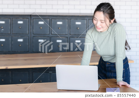 Beautiful Japanese woman smiling while looking at a computer There is a copy space Beautiful Japanese woman smiling while looking at a computer There is a copy space 85557440