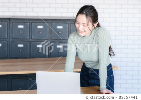 Beautiful Japanese woman smiling while looking at a computer There is a copy space Beautiful Japanese woman smiling while looking at a computer There is a copy space 85557441