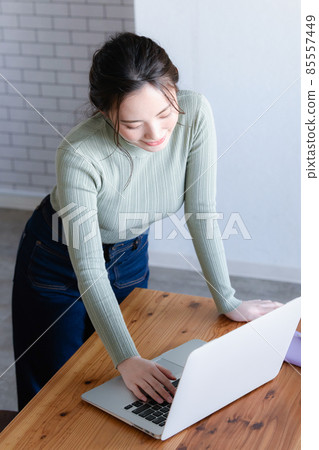 A beautiful Japanese woman with a smile while looking at a computer. There is a copy space. A little bird's-eye view. A beautiful Japanese woman with a smile while looking at a computer. There is a copy space. A little bird's-eye view. 85557449