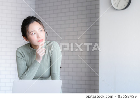 Japanese female thinking while using a computer There is a copy space Japanese female thinking while using a computer There is a copy space 85558459