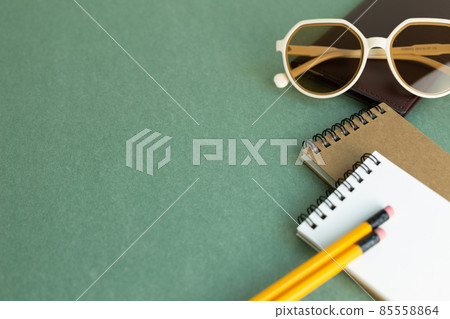 Various office supply stationery. notebook, glasses, pencil on green desk background with copy space Various office supply stationery. notebook, glasses, pencil on green desk background with copy space 85558864