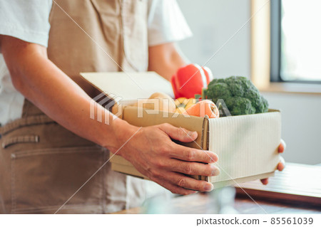 一個男人在廚房的紙板箱裡放著蔬菜 85561039