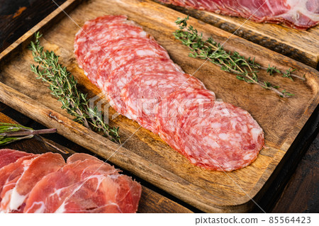 Meat antipasto, pancetta, salami, sliced ham prosciutto, on old dark wooden table background 85564423