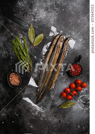 Smoked lamprey vacuum pack, on black dark stone table background, top view flat lay, with copy space for text 85564503