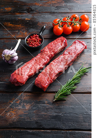 Denver steak two fresh, raw steaks from the cut of beef or organic top blade with herbs on old dark wooden table surface side view space for text vertical Denver steak two fresh, raw steaks from the cut of beef or organic top blade with herbs on old dark wooden table surface side view space for text vertical 85564815