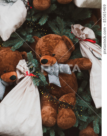 Soft brown bear toys on shop window Christmas fair store decorated with gifts garland lights illuminated New year retail 85565469