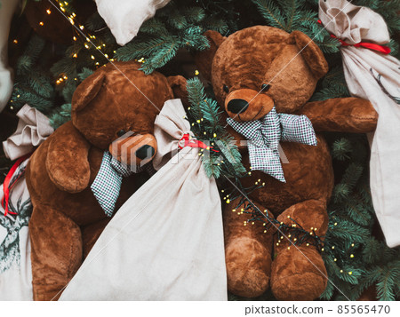 Soft brown bear toys on shop window Christmas fair store decorated with gifts garland lights illuminated New year retail 85565470