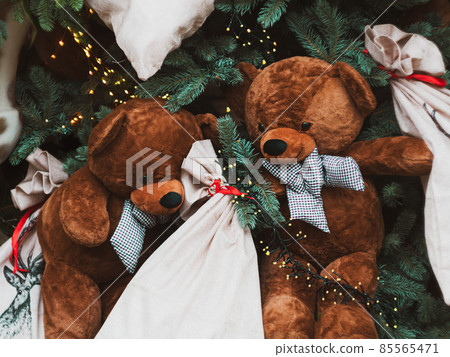Soft brown bear toys on shop window Christmas fair store decorated with gifts garland lights illuminated New year retail 85565471