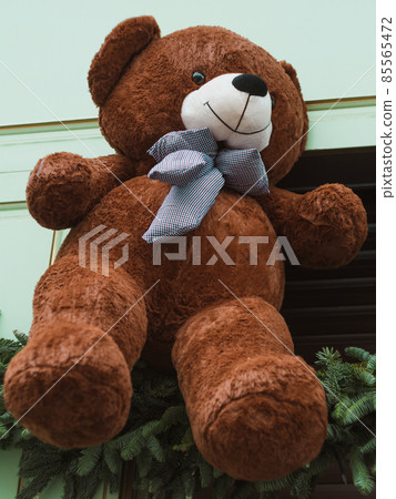 Soft brown bear toys on shop window Christmas fair store decorated with gifts garland lights illuminated New year retail 85565472