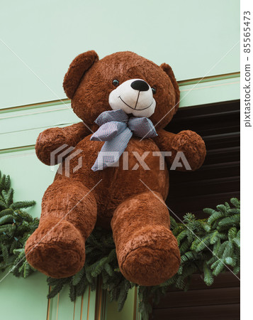 Soft brown bear toys on shop window Christmas fair store decorated with gifts garland lights illuminated New year retail Soft brown bear toys on shop window Christmas fair store decorated with gifts garland lights illuminated New year retail 85565473