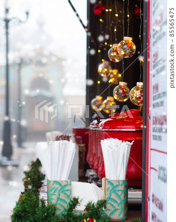 Red pots with mulled wine on Christmas market illuminated stall. Seasonal holiday street food beverages concept New year 85565475