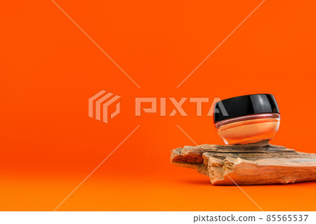 Cosmetic face BB cream tonal foundation glass jar mockup natural wood podium orange background. Balancing makeup product Cosmetic face BB cream tonal foundation glass jar mockup natural wood podium orange background. Balancing makeup product 85565537