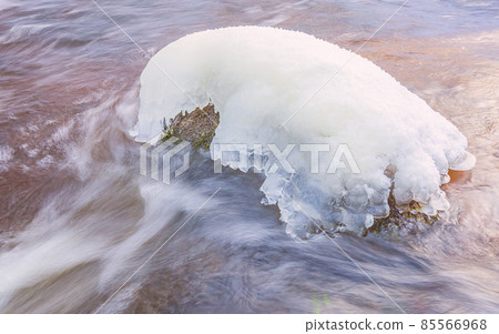 Icicles over the water in the river. Natural landscape. Winter. Background image. Icicles over the water in the river. Natural landscape. Winter. Background image. 85566968