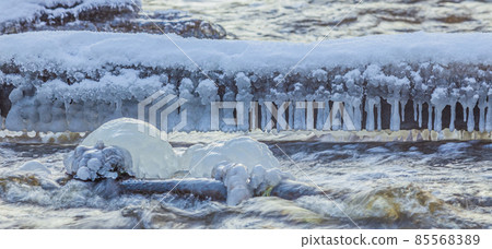 Icicles at winter, cold weather with icicles over river stream 85568389