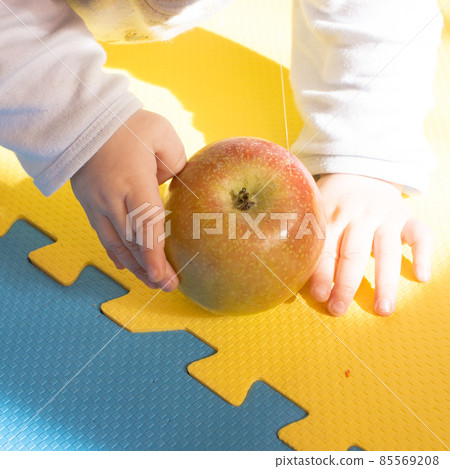 a child plays with a apple on the sill a child plays with a apple on the sill 85569208