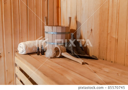 Traditional old Russian bathhouse SPA Concept. Interior details Finnish sauna steam room with traditional sauna accessories set basin towel aroma oil scoop felt. Relax country village bath concept 85570745