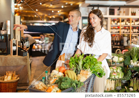 Portrait of a happy young couple in a supermarket with a full grocery cart 85573265