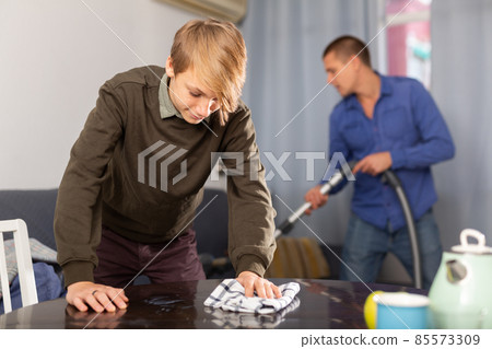 Teenager boy wiping dust from table Teenager boy wiping dust from table 85573309