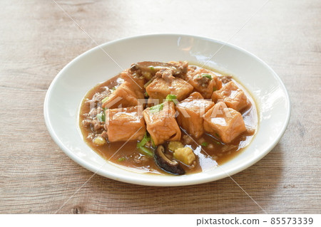 deep fried fish tofu with chop pork topping slice mushroom in sweet and sour gravy sauce on plate 85573339