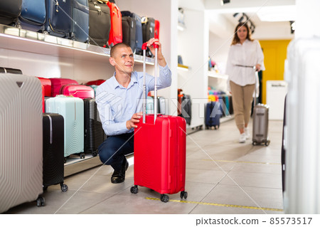 Positive male customer choosing travel suitcase in shop Positive male customer choosing travel suitcase in shop 85573517
