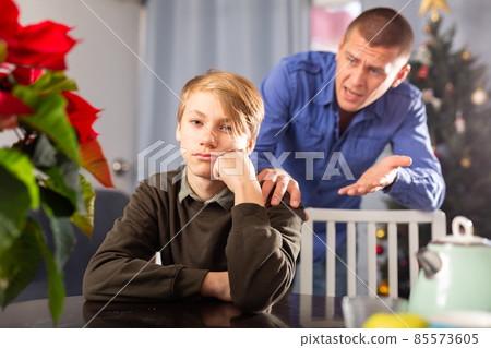 Father is unhappy with his son and expresses his displeasure during holiday of christmas Father is unhappy with his son and expresses his displeasure during holiday of christmas 85573605