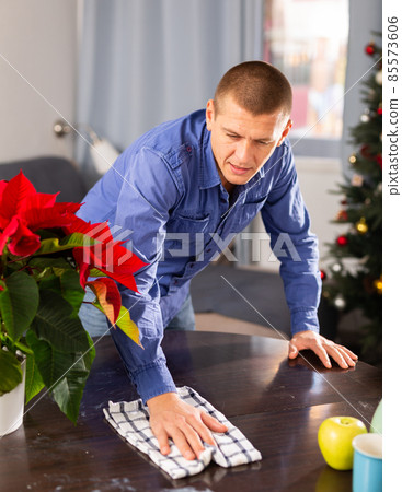 Man cleaning table with rag at home before christmas 85573606