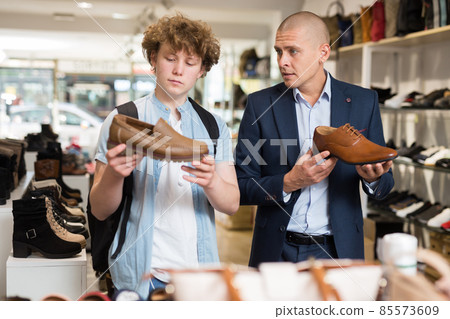Man and teenage boy choosing dress shoes in shoe boutique 85573609