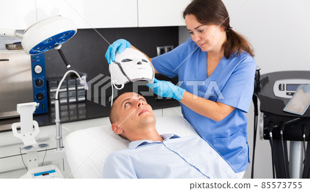 Man getting LED facial mask light therapy Man getting LED facial mask light therapy 85573755