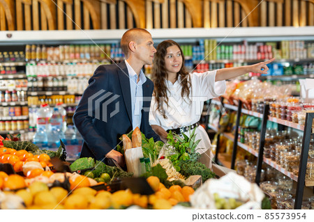 Portrait of a happy young couple in a supermarket with a full grocery cart 85573954