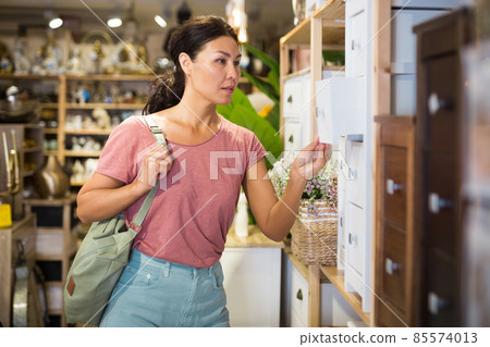Asian female choosing wooden commode in store Asian female choosing wooden commode in store 85574013