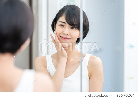 A woman checking the condition of her skin in the mirror A woman checking the condition of her skin in the mirror 85576204