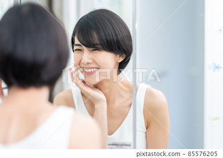 A woman checking the condition of her skin in the mirror A woman checking the condition of her skin in the mirror 85576205