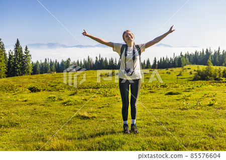 Traveler photographer with a camera alone view hands raised over clouds in the nature. Amazing Carpathians landscape background banner panorama Traveler photographer with a camera alone view hands raised over clouds in the nature. Amazing Carpathians landscape background banner panorama 85576604