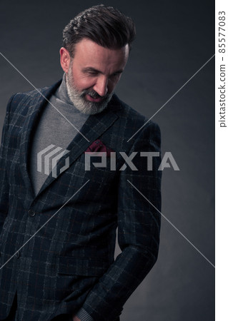 Portrait of a stylish elegant senior businessman with a beard and casual business clothes in photo studio isolated on dark background gesturing with hands Portrait of a stylish elegant senior businessman with a beard and casual business clothes in photo studio isolated on dark background gesturing with hands 85577083