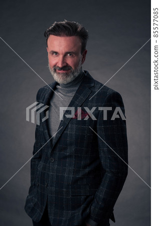 Portrait of a stylish elegant senior businessman with a beard and casual business clothes in photo studio isolated on dark background gesturing with hands Portrait of a stylish elegant senior businessman with a beard and casual business clothes in photo studio isolated on dark background gesturing with hands 85577085