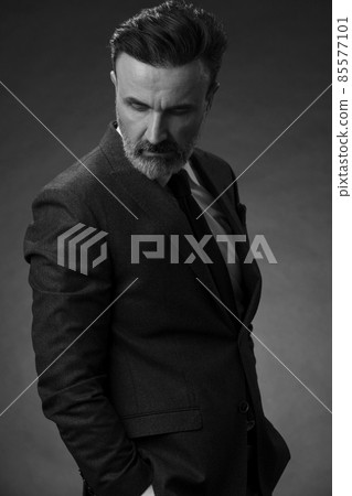 Portrait of a stylish elegant senior businessman with a beard and casual business clothes in photo studio isolated on dark background gesturing with hands Portrait of a stylish elegant senior businessman with a beard and casual business clothes in photo studio isolated on dark background gesturing with hands 85577101