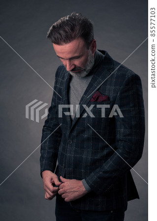 Portrait of a stylish elegant senior businessman with a beard and casual business clothes in photo studio isolated on dark background gesturing with hands Portrait of a stylish elegant senior businessman with a beard and casual business clothes in photo studio isolated on dark background gesturing with hands 85577103