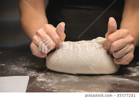 Close-up baker making bread, female hands, kneading dough, cooking 85577281