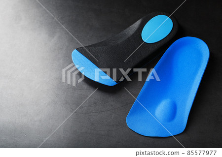 Orthopedic insoles for correction of pronation of the foot on a dark background. 85577977