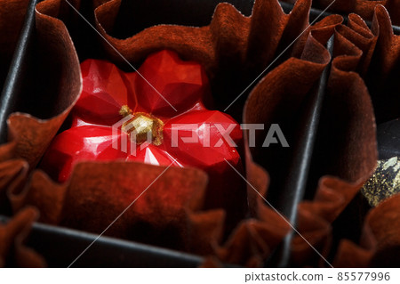 Exquisite handmade chocolate candy in the shape of a red flower close-up 85577996