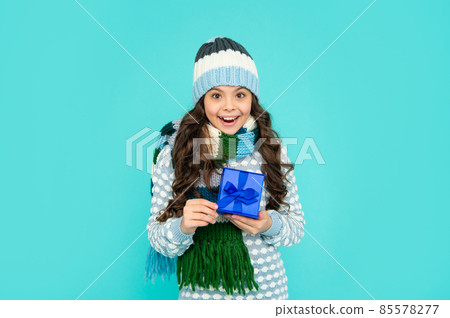 surprised happy child in knitwear hold box. kid with present. teen girl on blue background. 85578277