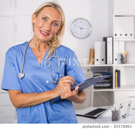 Female doctor writing notes on clipboard in clinic 85578863