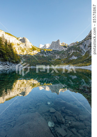 Beautiful view of idyllic colorful autumn scenery with Dachstein mountain summit reflecting in crystal clear Gosausee mountain lake in fall, Salzkammergut region, Upper Austria. Beautiful view of idyllic colorful autumn scenery with Dachstein mountain summit reflecting in crystal clear Gosausee mountain lake in fall, Salzkammergut region, Upper Austria. 85578867